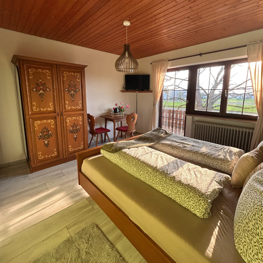 Gemütliches Doppelzimmer im Landhausstil mit antikem Schrank, Schreibtisch und Blick auf Felder – Ferienwohnung Lindenhof Worblingen.